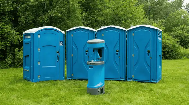 Four blue portable toilets and a matching hand washing station on grass near trees, a common sight at local outdoor events in Chandler, AZ
